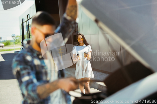 Image of Young couple preparing for vacation trip on the car in sunny day