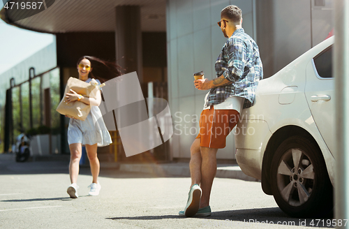 Image of Young couple preparing for vacation trip on the car in sunny day