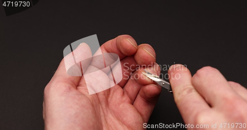 Image of Man cuts fingernail for himself