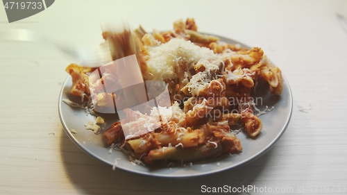 Image of Cheese topping beiing applied to bowl of pasta