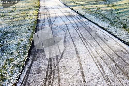 Image of footprints and bicycle tracks on the track covered with the firs