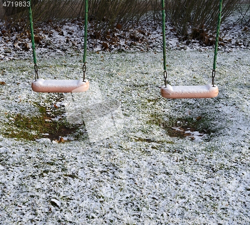 Image of children's swing in the yard covered with the snow