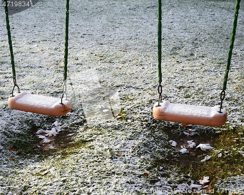 Image of children's swing in the yard covered with the snow