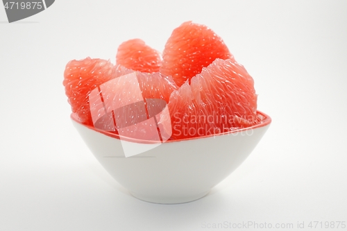 Image of juicy red grapefruit slices in a bowl on a white 