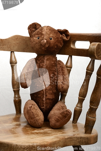 Image of teddy bear sitting in an old vintage wooden armchair