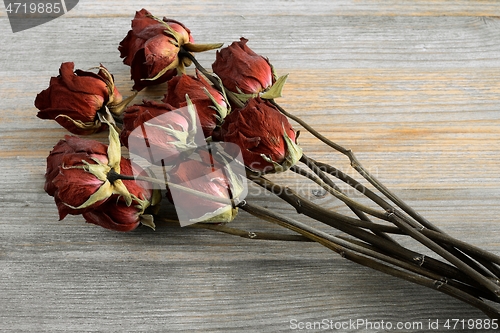 Image of bouquet of withered roses on a wooden
