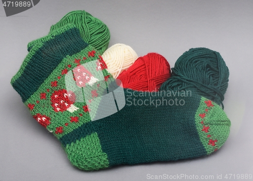 Image of a woolen socks with amanita print and skeins of thread