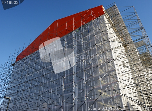 Image of building in scaffolding during renovation against blue sky 