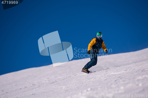 Image of snowboarder running down the slope and ride free style