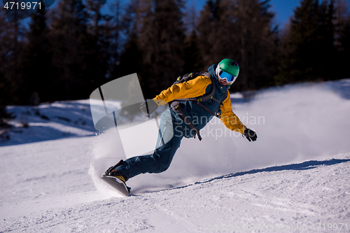 Image of snowboarder running down the slope and ride free style