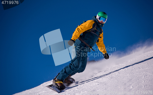 Image of snowboarder running down the slope and ride free style