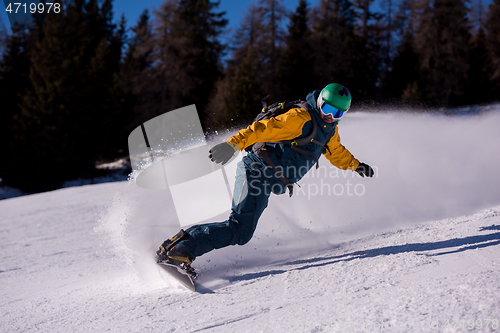 Image of snowboarder running down the slope and ride free style