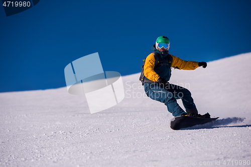 Image of snowboarder running down the slope and ride free style