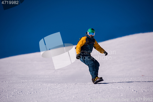 Image of snowboarder running down the slope and ride free style