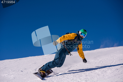 Image of snowboarder running down the slope and ride free style