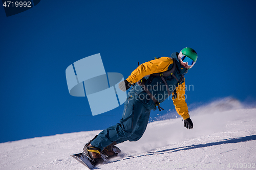 Image of snowboarder running down the slope and ride free style