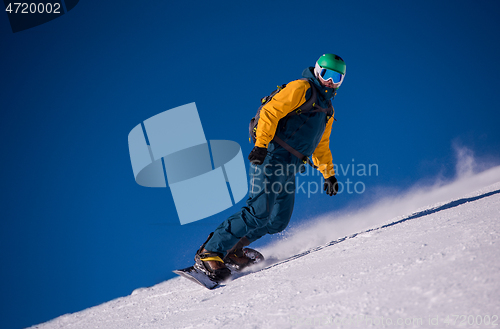 Image of snowboarder running down the slope and ride free style