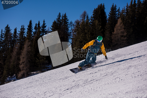 Image of snowboarder running down the slope and ride free style