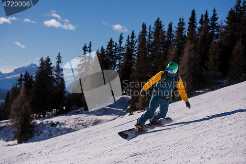 Image of snowboarder running down the slope and ride free style