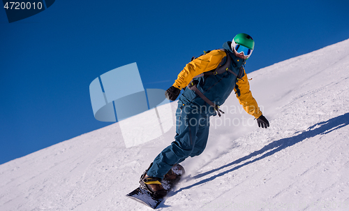 Image of snowboarder running down the slope and ride free style