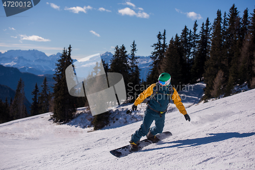 Image of snowboarder running down the slope and ride free style