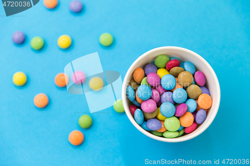 Image of candy drops in paper cup on blue background