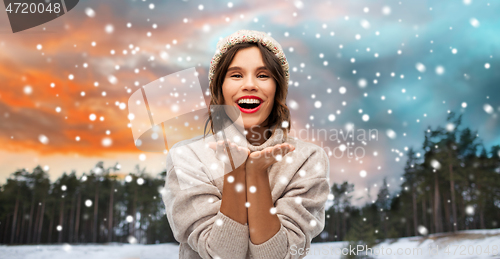 Image of woman in hat sending air kiss over winter forest