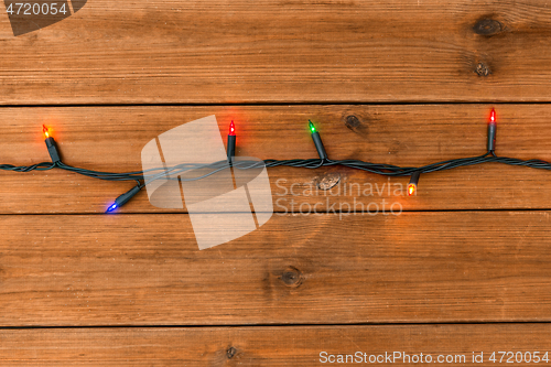 Image of christmas garland lights on wooden background