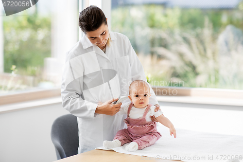 Image of doctor with thermometer measures baby temperature