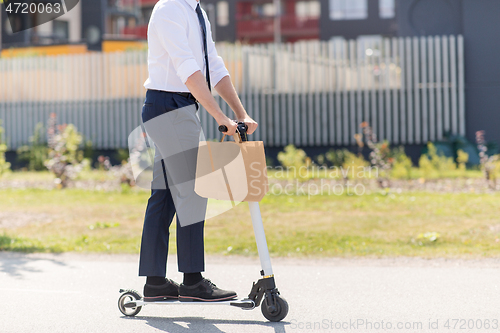 Image of businessman with takeaway paper bag riding scooter