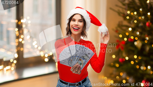 Image of happy woman in santa hat with money on christmas