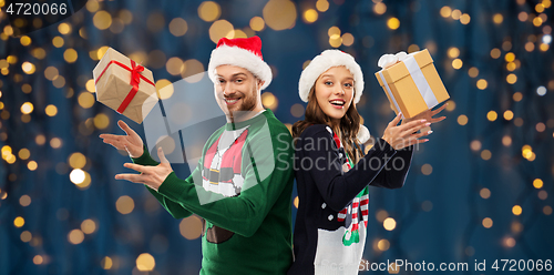 Image of happy couple in christmas sweaters with gifts