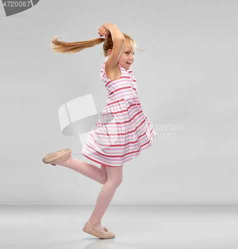 Image of happy little girl in striped dress jumping