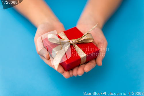 Image of hands holding red small christmas gift box