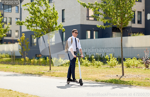 Image of businessman with backpack riding electric scooter