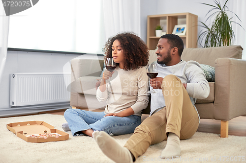 Image of happy couple with wine and takeaway pizza at home