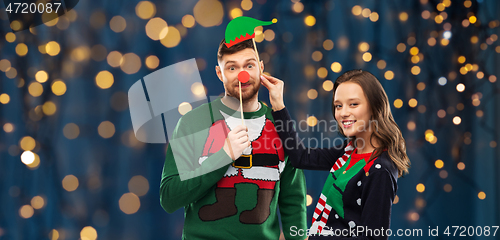 Image of couple with christmas party props in ugly sweaters