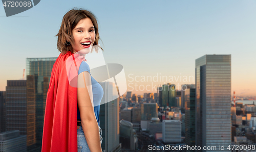 Image of happy woman in red superhero cape over tokyo city