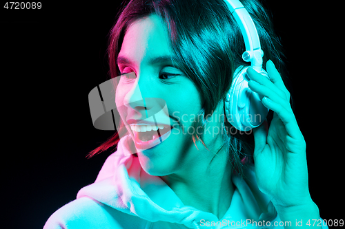 Image of woman in headphones listening to music in neon