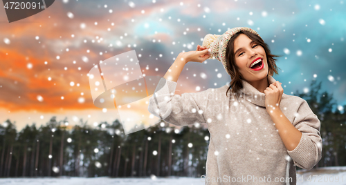 Image of woman in hat and sweater over winter forest