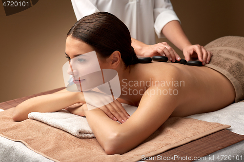 Image of beautiful woman having hot stone massage at spa