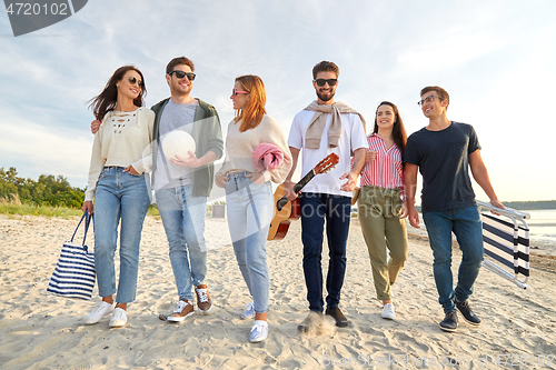 Image of happy friends walking along summer beach