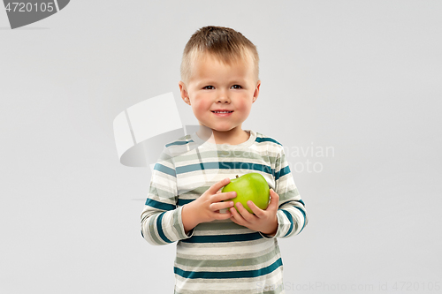Image of portrait of smiling boy holding green apple