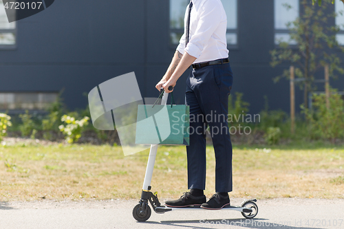 Image of businessman with shopping bag riding scooter