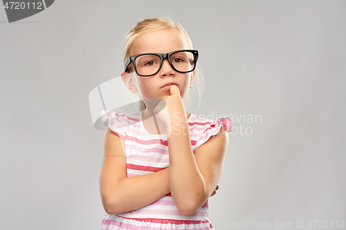 Image of cute little girl in black glasses thinking