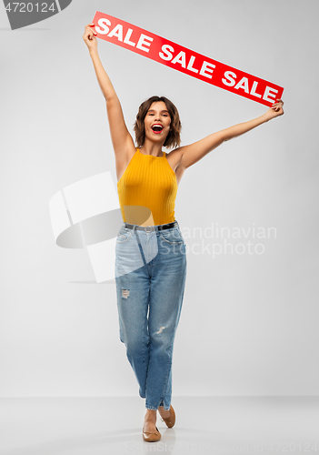 Image of happy smiling young woman posing with sale banner