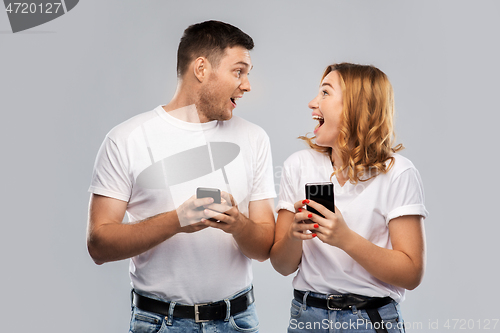 Image of happy couple in white t-shirts with smartphones