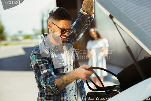 Image of Young couple preparing for vacation trip on the car in sunny day