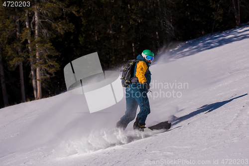 Image of snowboarder running down the slope and ride free style