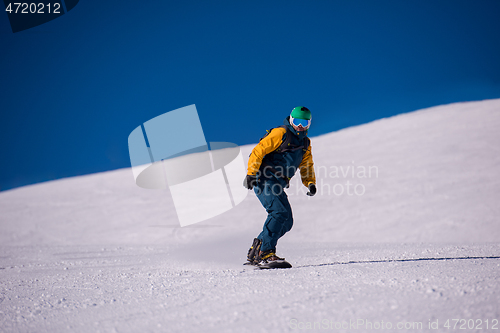 Image of snowboarder running down the slope and ride free style